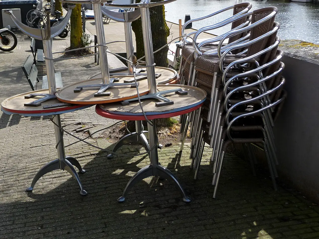 Stapels terrasstoelen en terrastafels opgeslagen langs de Entrepotdok in Amsterdam